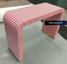 a red and white striped bench sitting on top of a metal floor next to a roll of paper