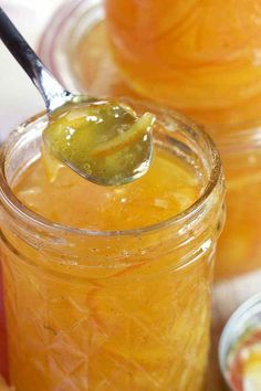 a spoon full of pickled up oranges in mason jars