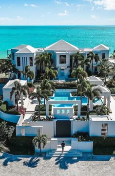 an aerial view of a house with palm trees and the ocean in the back ground