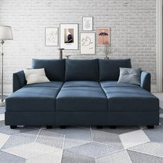 a blue couch sitting on top of a white floor next to a lamp and pictures