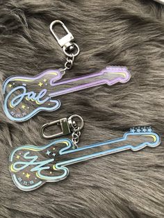 three guitar shaped key chains on top of a furry surface