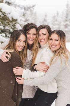 four women hugging each other in the snow