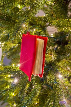 an ornament hanging from a christmas tree in the shape of a book on it