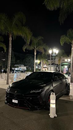 a black sports car parked in front of a parking meter at night with palm trees