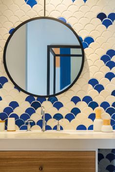 a bathroom sink with a mirror above it and blue fish scale tiles on the wall