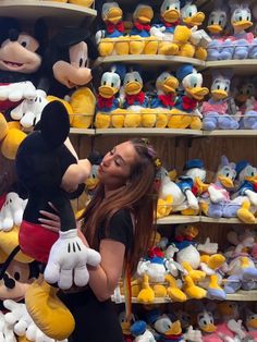 a woman standing in front of mickey mouse stuffed animals