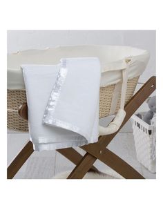 a white blanket sitting on top of a wooden chair next to a basket filled with items