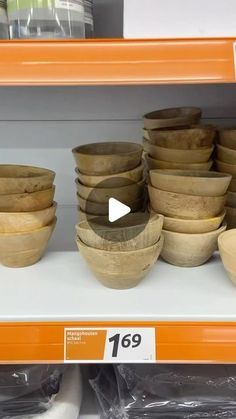 wooden bowls are on display for sale in a store shelf, with the price tag below them