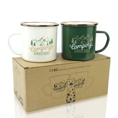 two coffee mugs sitting on top of a box with the same logo and color