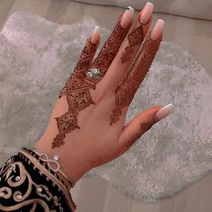 a woman's hand with henna tattoos and jewelry on top of her arm