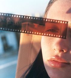 a woman holding up a film strip to her face