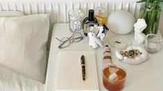 an assortment of items sitting on top of a white table next to a pillow and vase