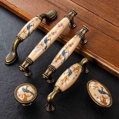 four antique style handles and knobs on a black surface with wood trimming in the background