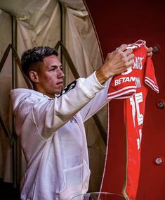 a man holding up a red and white shirt