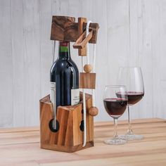 a wine bottle and two glasses on a wooden table next to a corkscrew