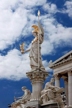 a statue on top of a building with clouds in the background