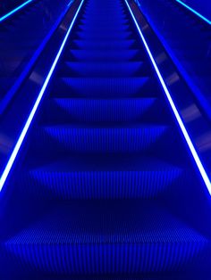 an escalator with blue lights going down it