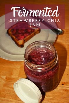 a jar of strawberry jam next to a plate with toast on it and the words fermented strawberry - berry - chia jam