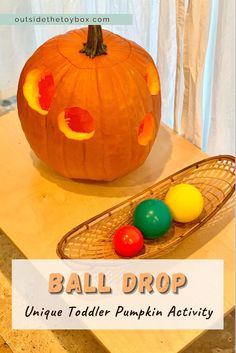 an orange pumpkin sitting on top of a wooden table next to three colorful plastic balls