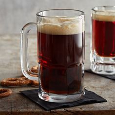 two mugs filled with beer sitting on top of a wooden table