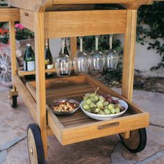 a wooden cart filled with wine glasses and food