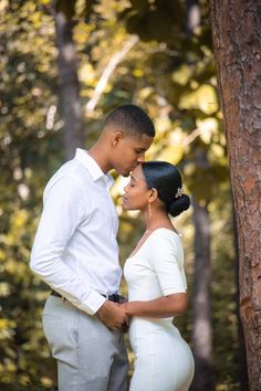 a man and woman standing next to each other in the woods