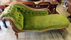 a green couch sitting on top of a wooden floor next to a dining room table