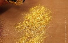 someone is painting gold glitter on a piece of paper