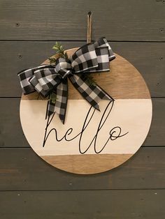 a wooden sign with the word hello written on it and a bow tied to it