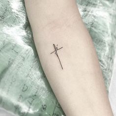 a small tattoo on the arm of a person with a cross in it's middle