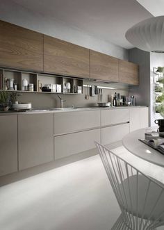 a modern kitchen with white counter tops and wooden cabinets, along with a large window