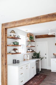 a white kitchen with open shelving above the sink