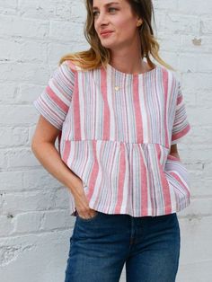 a woman standing in front of a white brick wall with her hands on her hips