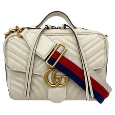 Gucci GG Marmont Matelasse Top Handle Flap Bag in fair condition. Cream matelasse chevron quilted leather exterior trimmed with antiqued brass hardware and removable blue red and white striped canvas shoulder strap. Front flap pocket with GG hardware. Top handle that slides up and down to suit your style. Double zip closure opens 3 sides to a tan suede interior with one zipped and one slit side pockets. Wear on exterior bottom corners and sides. small stains on interior lining. pen mark and scuf Gucci Marmont Top Handle Bag, Gucci Gg Marmont Matelasse, Leather Camera Bag, Exterior Details, Gucci Gg Marmont, Antique Brass Hardware, Chevron Quilt, Gg Marmont, Tan Suede