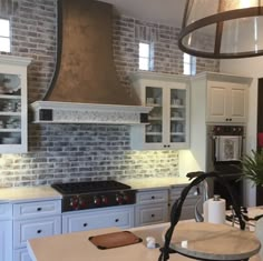 a kitchen with white cabinets and an oven in the center, surrounded by brick walls