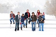 a group of people standing on top of a snow covered field next to a fence