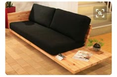 a black couch sitting on top of a wooden coffee table next to a stair case