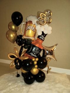 a table topped with balloons and black and gold decorations, including beer bottles in the center