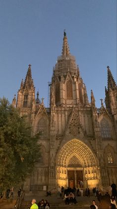 people are sitting on the steps in front of an old cathedral