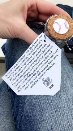 a person is holding a baseball in a jar with a paper tag attached to it