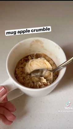 someone is holding a spoon in a bowl of cereal with ice cream on top and the words mug apple crumble above it