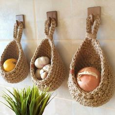 three baskets are hanging on the wall next to a potted plant and an orange