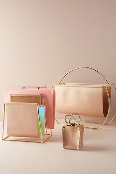 three purses, one in gold and one in pink are sitting on a table