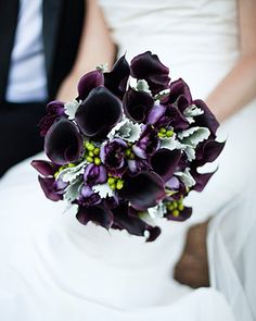 a bride holding a purple and white bouquet with black calla lilies on it