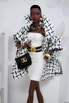 a black and white barbie doll wearing a dress with gold accessories, holding a chandelier