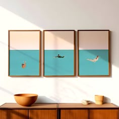 two framed pictures hang on the wall above a dresser with a bowl and vase in front of it