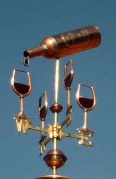 a wine glass and bottle on top of a weather vane