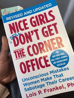 a person holding up a book about nice girls don't get the corner office