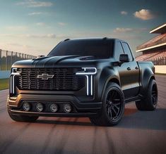 the front end of a black truck on a race track