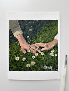 two hands touching each other in the grass with daisies on it and one hand holding another's hand